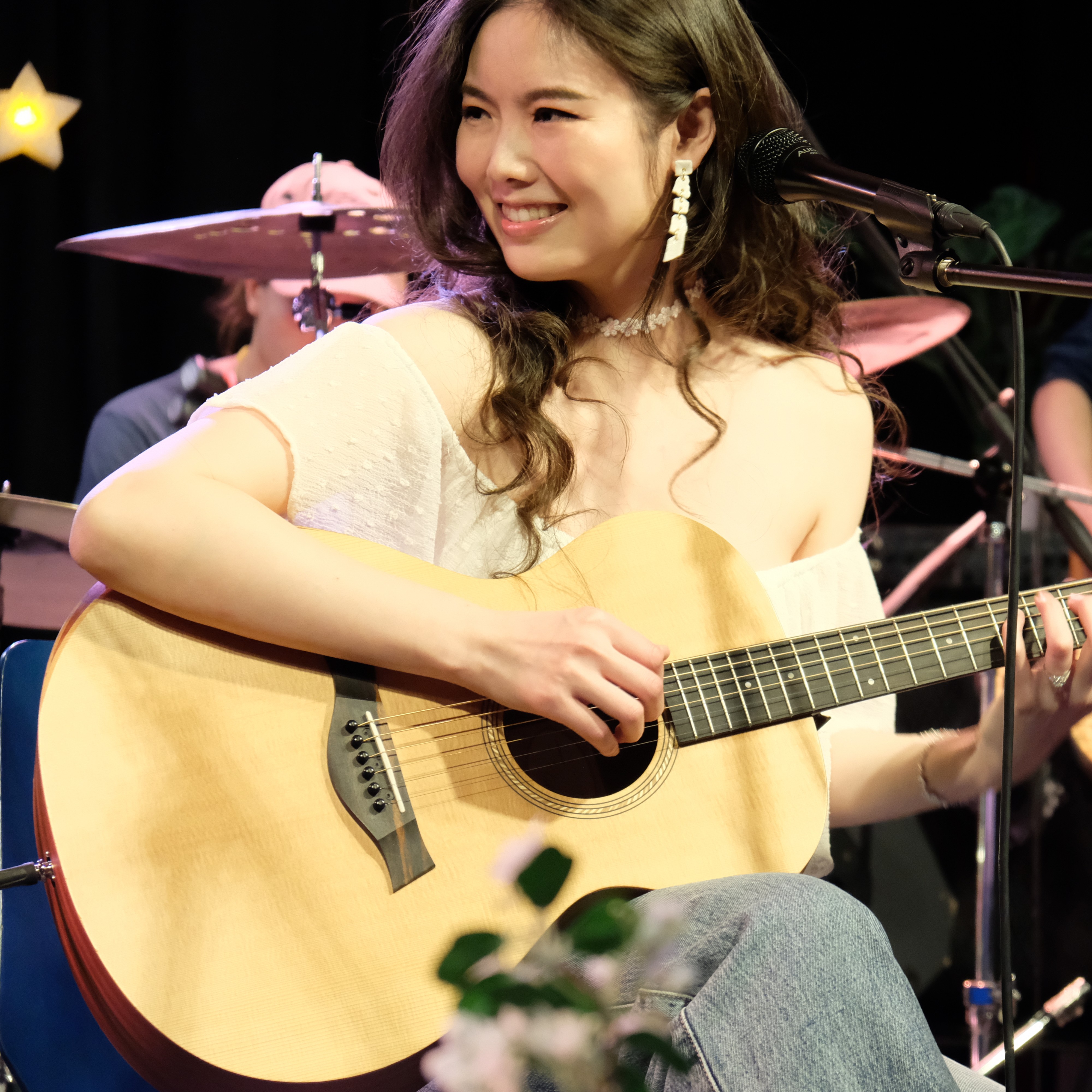 Xiao smiling while playing acoustic guitar on stage